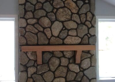 large round stone surround with wood beam mantel