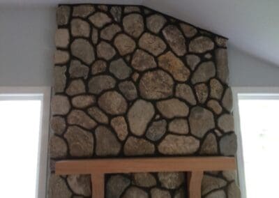 large round stone surround with wood beam mantel
